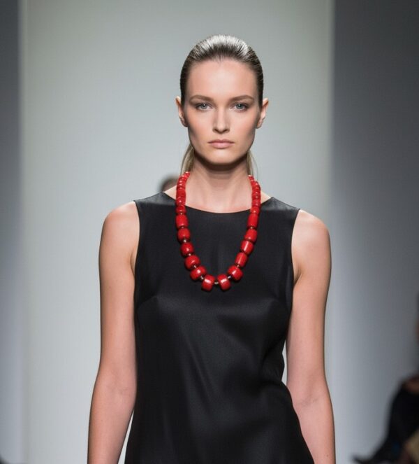❤️ Bold and radiant, the Coral Necklace is a handcrafted masterpiece that captures the essence of passion and purpose. Measuring just right for statement-making elegance, this exquisite piece features an arresting combination of natural, deep red coral beads—each expertly polished and sculpted into sleek cylindrical shapes. The rich color tones evoke a sense of vitality, warmth, and confidence, making it a standout accessory for day or night. A sophisticated black stone toggle clasp anchors the design with subtle contrast, balancing the fiery coral with understated refinement. The juxtaposition creates an alluring harmony that draws the eye and complements any wardrobe palette. More than just a stunning piece, the coral carries deep cultural and spiritual meaning. Revered for its ability to promote awakening and guide one toward a successful life, it has been worn throughout history as a symbol of strength and insight. This design is no coincidence—it reinforces the necklace’s fiery spirit and its energizing impact on both style and soul.  Wear the Coral Necklace as a personal emblem of bold beauty and inner empowerment. Let its color ignite your confidence and its craftsmanship speak to your story—striking, soulful, and distinctly you.