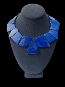 💙 Crafted for bold individuality, the Lapis Lazuli Necklace is a captivating exploration of color, shape, and form. Measuring 17 inches and weighing 7 ounces, it offers a substantial presence while remaining wearable for both casual and elevated occasions. At its center lies a commanding 2-inch bead, a polished showpiece that sets the tone for the necklace’s sculptural charm. This handcrafted design showcases a large-cut, genuine natural stone of Lapis Lazuli—revered for its rich, deep blue color and subtle flecks of gold. The stone’s surface glimmers with earthy texture and quiet drama, embodying centuries of admiration for its symbolism of wisdom and royalty. What makes this necklace distinct is its asymmetric layout. Each bead, carved in irregular shapes and sizes, is arranged in a non-uniform sequence that plays with dimension and movement. This asymmetric pattern invites the eye to wander, echoing the spontaneity of nature and the beauty of imperfection. The final touch of refinement lies in its intentional structure—a thoughtfully balanced design in which the asymmetric elements feel intentional, not accidental. It’s a piece that defies symmetry to celebrate uniqueness. For collectors, creatives, and those who lean into visual expression, the Lapis Lazuli Necklace offers a bold narrative—fluid, powerful, and distinctively formed.
