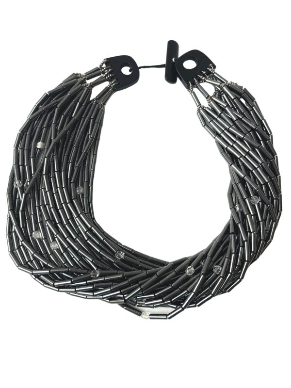 Hematite is more silver than black. This necklace has accent faceted crystals, making an even more lustrous combination with the silver color of the Hematite. The necklace has 24 Hematite strands, one crystal in each strand, and a natural Onix toggle clasp. The shortest strand, or the closest to the neckline, measures (+/-) 19 IN, and the longest measures (+/-) 24 IN. The necklace weighs 20 OZ. There are several ways to display its splendor: flat, twisted, crossing strands, and wearing the clasp at the front or back of the neck.