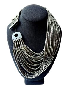 🌒 A statement in sophistication and strength, the Hematite Necklace embodies bold design with a shimmering touch. Handcrafted with 24 gleaming strands, this piece offers a dynamic combination of texture, light, and history. Measuring 19 inches at its shortest and extending up to 24 inches, its generous weight of 20 ounces enhances its luxurious presence while remaining comfortably wearable. Each strand is adorned with a faceted crystal, lending brilliance and movement to the overall silhouette. The lustrous silver tone of Hematite creates an elegant backdrop, contrasting beautifully with the sparkle of the crystals and the deep tones of the Onyx toggle clasp. This adjustable clasp allows the necklace to be styled in multiple ways—flat across the collarbone, twisted for volume, or crossed for an avant-garde edge. Whether worn with the clasp in front or back, every arrangement offers a new mood and visual rhythm. Historically, Hematite held symbolic significance—it was worn as a talisman by English warriors, believed to safeguard those wounded in battle. Its inclusion here infuses the necklace with quiet power and cultural depth. Perfect for collectors of meaningful jewelry and lovers of sculptural elegance, this piece invites admiration for its craftsmanship and versatility. The final whisper of Hematite completes its story—resilient, radiant, and unapologetically bold.