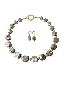 Natural unpolished Pyrite crystals with Zirconia and gold-plated spacer beads. The color is gray platinum, measuring 20 IN/10 OZ. This is a set with the earring of the same materials. The stones have the natural formation of the Pyrite minerals.