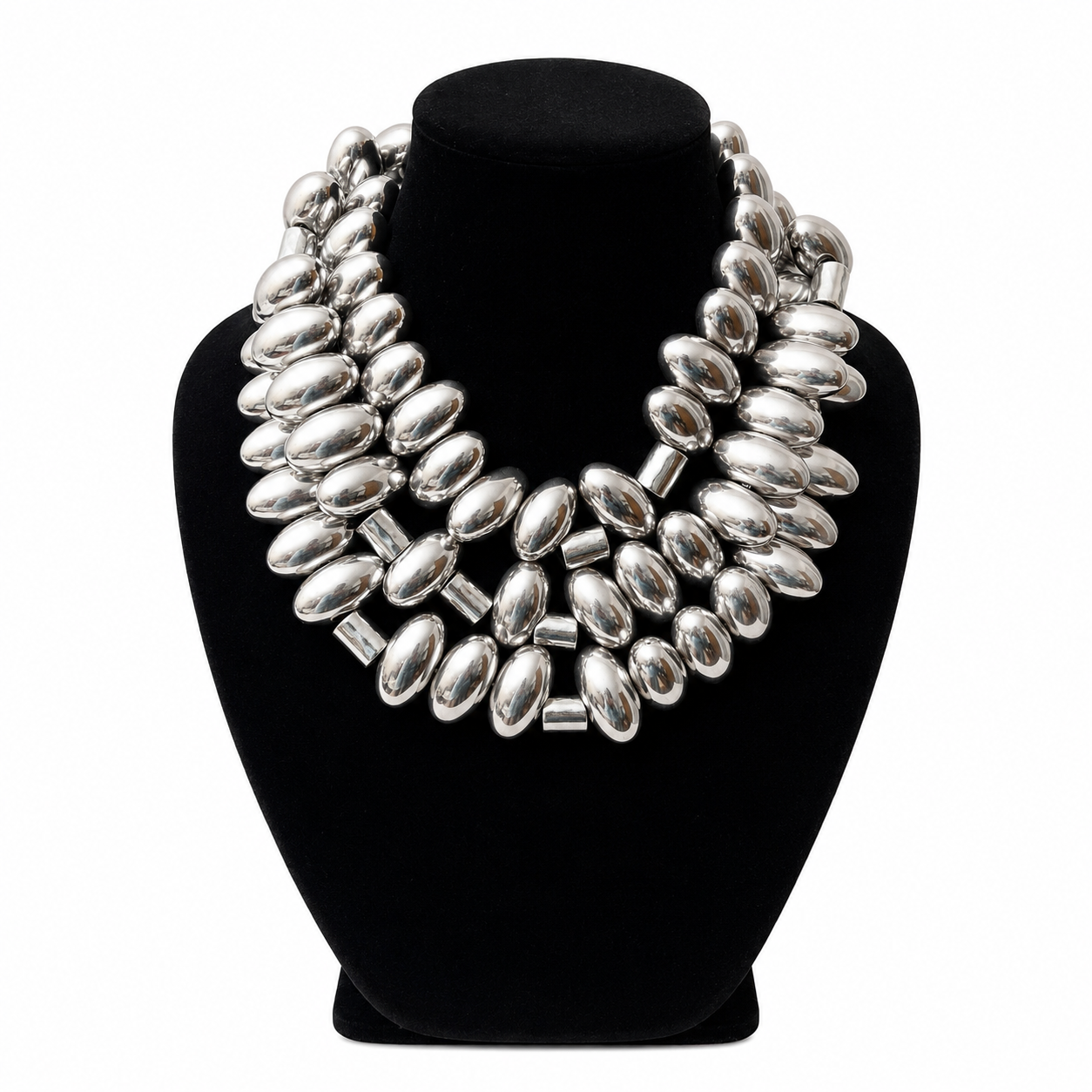 Close-up of the Silver Bullets Necklace featuring elongated oval-shaped metallic beads with a mirror-like chrome finish, strung together with small cylindrical spacers. The necklace is coiled neatly on a white background, showcasing its reflective surface and craftsmanship.