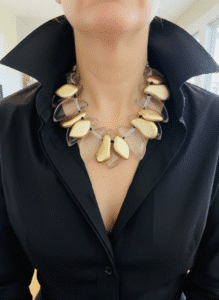 🌟 Refined yet expressive, this statement necklace commands attention with its sculptural charm and luminous palette. Measuring 20 inches and weighing 15 ounces, it offers substantial presence while maintaining a comfortable drape against the collarbone. Designed to impress, this piece strikes the perfect balance between elegance and bold artistry. The necklace showcases a single strand expertly arranged with large, clear beads and uniquely shaped accents reminiscent of gold leaf. These golden elements shimmer gently, adding depth and warmth without overwhelming the composition. Interspersed among the clear beads, each gold leaf-shaped piece offers a naturalistic flow that evokes movement and organic grace. As a neutral-toned creation, the pairing of transparent brilliance and metallic gleam makes this necklace an adaptable addition to any wardrobe. Whether styled with daytime neutrals or paired with an evening ensemble, its versatility ensures it enhances without competing. What elevates this piece beyond accessory status is the thoughtful clustering of elements. By blending clear forms with strategically placed gold leaf accents, the design achieves a sophisticated harmony—clean, artistic, and full of character. With the final touch of gold leaf completing the triad of sparkle, this necklace becomes more than jewelry—it becomes your signature piece for radiant self-expression.