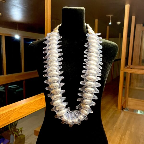 Adornment meets innovation in this stunning necklace, where large, oval silver beads are elegantly encapsulated in a shimmering blue metal mesh. The layers glint, shining like a photophore.  The striking contrast between the bright silver beads and the sleek deep-blue mesh creates a look that balances boldness with ease. Each bead nestles within the mesh, forming a cohesive thread that drapes fluidly yet holds its sculptural integrity. Designed for versatile wear, the piece can hang long for a graceful silhouette or be doubled into a chunky, stacked statement that hugs the neckline. Its fluidity allows it to complement minimalist dresses or be layered with other necklaces for a maximalist approach. The silver beads, reminiscent of marine photophores, reflect their own brilliance through the delicate mesh, creating a mesmerizing interplay of light and shadow.  The luminous shine of the encapsulated beads ensures this necklace captures attention from every angle. Handcrafted with skill, this piece merges modern industrial flair with timeless sophistication. It pairs effortlessly with tailored suiting, soft silks, or casual denim, adapting to both daywear and evening couture. Truly perfect as a gift or indulgence, this necklace is more than jewelry—it’s a wearable art piece. Embrace the allure of this photophore-inspired design and transform your wardrobe with unparalleled elegance.