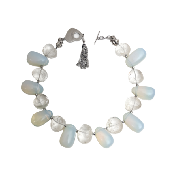 Experience the enchantment of natural beauty and artistry with our handcrafted necklace featuring luminous gemstones. This extraordinary piece showcases an elegant interplay between two distinct bead types, marrying subtle opalescence with earthy sophistication. The design revolves around the seamless union of Opalite Crystal beads and genuine Crystal Rock beads. Each element captures and reflects light in its own unique way, creating a dynamic dance of brilliance with every movement. The Opalite Crystal strands reveal a mesmerizing color effect that shifts from soft green to pale blue, lending the necklace an ethereal quality that changes with each glance. Complementing these hues, the Crystal Rock beads provide structure and clarity, grounding the iridescent glow in polished elegance. Capable of harmonizing with virtually any outfit, this versatile accessory transitions seamlessly from casual to formal settings. Whether paired with a crisp white blouse or a sleek evening gown, the subtle sparkle of Opalite Crystal details creates an eye-catching focal point without overwhelming the ensemble. More than an ornament, this necklace stands as a work of art, connecting fashion with raw earth elegance. The interplay of transparent beads and natural textures delivers a distinctive organic look, highlighting both craftsmanship and mindful design. Enhance your collection with this piece that brings a luminous perspective to any wardrobe.
