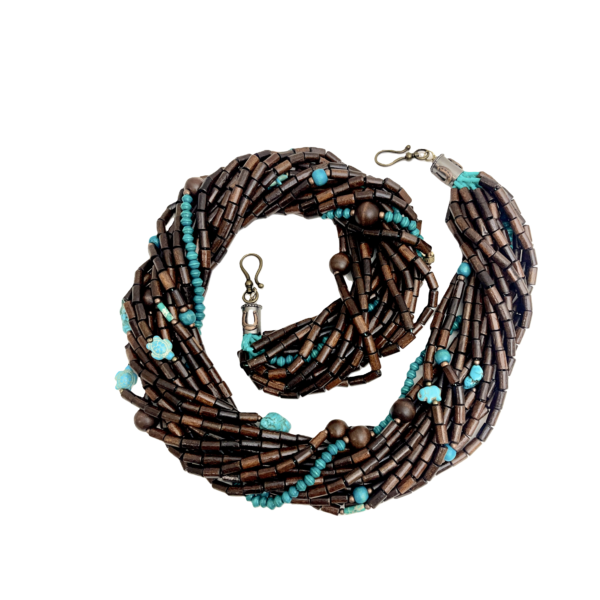 This exquisite multi-strand necklace is practical in every sense, seamlessly blending style and functionality. Handcrafted with care, it features polished wooden beads that showcase their warm, natural tones alongside vibrant turquoise accents that inject a burst of color into any look. The combination creates a striking visual appeal that feels both grounded and fresh. Measuring 38 inches when worn as a single strand, the necklace hangs gracefully, draping around the neck in elegant layers. Its versatile horseshoe clasp design offers a practical way for styling options, allowing you to double it up into a chic choker for a completely different vibe. This duality makes the piece practical for everyday wear and ideal for special occasions alike. Each bead is meticulously chosen to ensure uniformity in shape and color, resulting in a harmonious flow that highlights the contrast between deep wood grains and the bright turquoise hue. The horseshoe clasp, with its smooth curves and secure closure, adds a refined touch, reinforcing the necklace’s blend of artisanal craftsmanship and modern sensibility. Whether you’re dressing up a simple blouse or accentuating a formal gown, this statement necklace elevates your ensemble with ease. It’s the perfect accessory for those who appreciate adaptive design and enduring beauty.