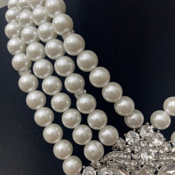 Multistrand necklace of simulation pearls and accent silver beads on an extra large brooch.