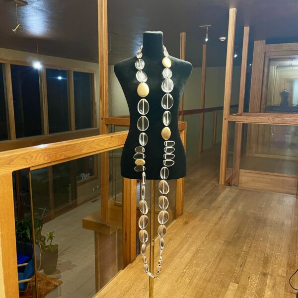 This exquisite, extra-long necklace features a stunning combination of clear beads interspersed with elegant gold accent beads, creating a sophisticated and eye-catching accessory. The harmonious blend of clear and gold tones adds a touch of luxury.  