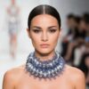 Model wearing Photophore Necklace with silver beads and blue mesh design styled as a bold sculptural choker on runway.