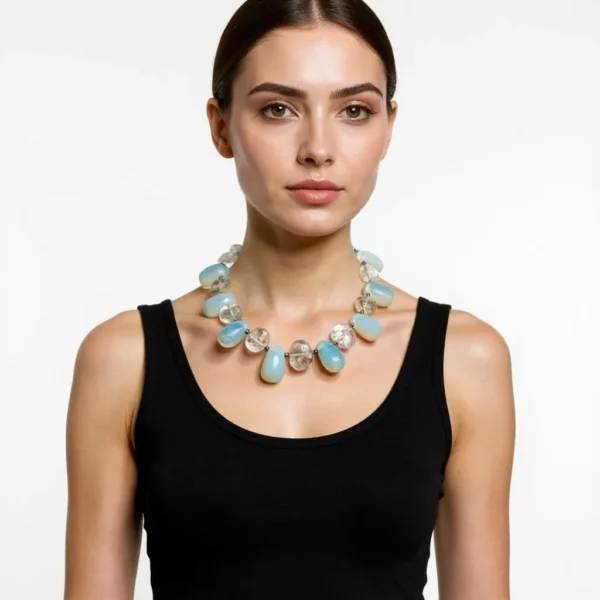 Experience the enchantment of natural beauty and artistry with our handcrafted necklace featuring luminous gemstones. This extraordinary piece showcases an elegant interplay between two distinct bead types, marrying subtle opalescence with earthy sophistication. The design revolves around the seamless union of Opalite Crystal beads and genuine Crystal Rock beads. Each element captures and reflects light in its own unique way, creating a dynamic dance of brilliance with every movement. The Opalite Crystal strands reveal a mesmerizing color effect that shifts from soft green to pale blue, lending the necklace an ethereal quality that changes with each glance. Complementing these hues, the Crystal Rock beads provide structure and clarity, grounding the iridescent glow in polished elegance. Capable of harmonizing with virtually any outfit, this versatile accessory transitions seamlessly from casual to formal settings. Whether paired with a crisp white blouse or a sleek evening gown, the subtle sparkle of Opalite Crystal details creates an eye-catching focal point without overwhelming the ensemble. More than an ornament, this necklace stands as a work of art, connecting fashion with raw earth elegance. The interplay of transparent beads and natural textures delivers a distinctive organic look, highlighting both craftsmanship and mindful design. Enhance your collection with this piece that brings a luminous perspective to any wardrobe.