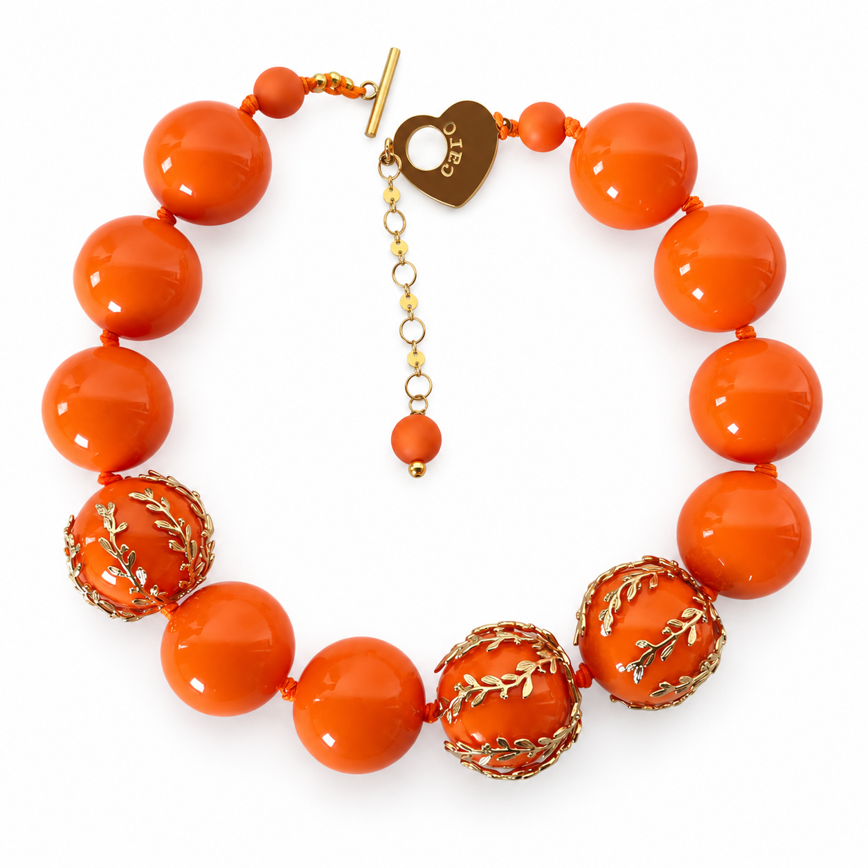 Bold statement necklace featuring large glossy orange acrylic beads with three gold‑accented filigree beads, displayed on a white background.