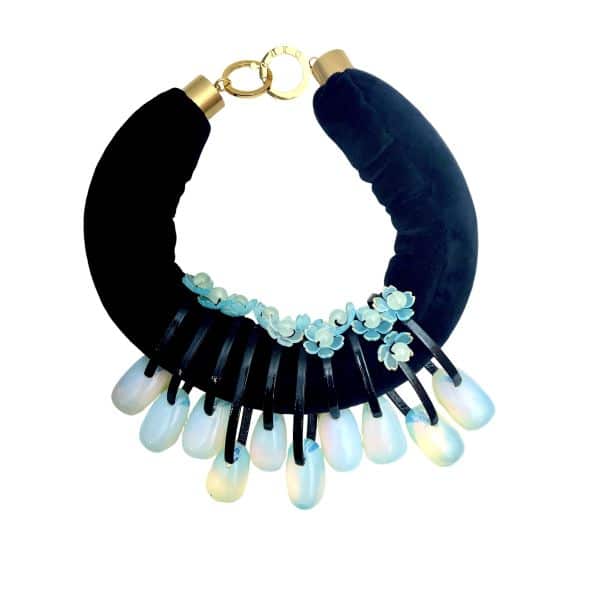 Translucent Opalite Velvet Choker Necklace Step into the light with this mesmerizing choker necklace, where beauty meets bold design.  Featuring large, dangling Opalite beads suspended from a double velvet cord, this piece is crafted to capture attention.  The bead's color allows light to pass through and dance across its surface, creating a subtle shimmer that shifts between blue and green tones depending on your surroundings. The dual velvet strands offer a rich contrast to the glass-like beads.  Whether worn with a plunging neckline or layered over a high collar, this choker adds a touch of ethereal elegance. • 💎 Materials:  Opalite beads • 🎨 Color: Hues of blue and green, depending on the surroundings • 🔗 Design: Asymmetric dangling beads Perfect for evening wear, artistic ensembles, or everyday magic, this necklace invites compliments and conversation. The translucent nature of Opalite makes each piece feel alive—responding to light, mood, and movement. Let your jewelry reflect your radiance. This choker isn’t just an accessory—it’s a luminous expression of your unique style.  The necklace's weight is 9 oz, and it is 18 in long.