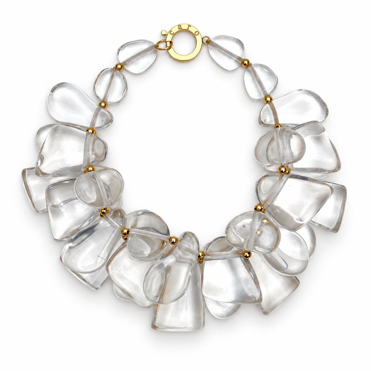 Clear acrylic cluster necklace featuring sculptural, irregularly shaped beads separated by gold spacers and secured with a round gold clasp engraved with “caro.”