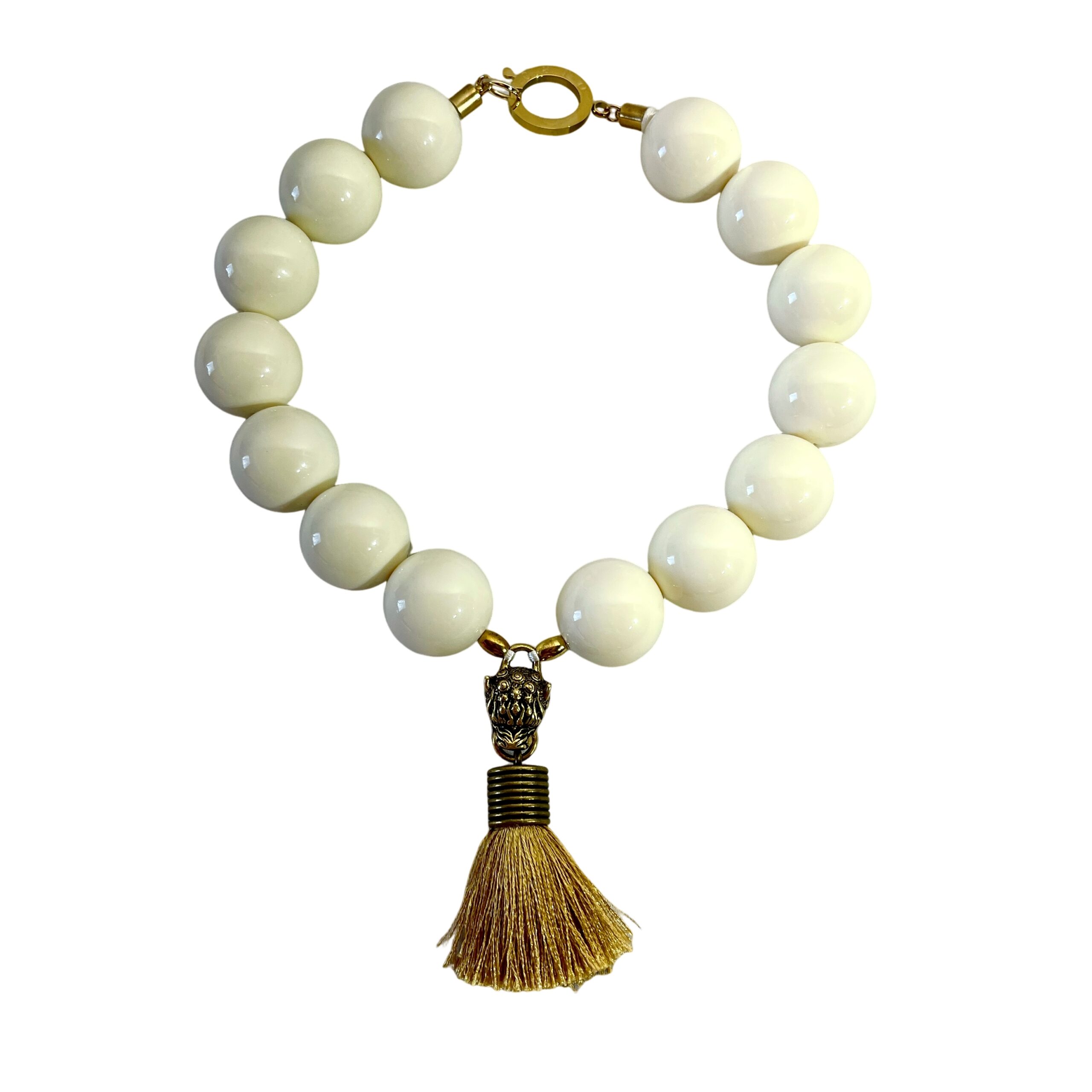 Elevate your style with this bold and elegant choker necklace, crafted from large cream-colored beads that exude timeless sophistication.  Measuring 19 inches in length and weighing 9 ounces, this statement piece balances substantial presence with refined detail.  Each glossy bead is carefully arranged to create a harmonious circular silhouette, anchored by a striking Mastiff pendant that commands attention. The pendant features a regal Mastiff motif, sculpted with intricate detail and finished in a rich gold tone.  From its mouth hangs a luxurious tassel, adding movement and texture to the design.  This symbolic centerpiece evokes strength, loyalty, and grace—perfect for those who appreciate jewelry with meaning. A large lobster clasp ensures secure fastening and ease of wear, while complementing the necklace’s bold aesthetic.  Whether paired with evening attire or used to elevate a casual ensemble, this choker offers versatility and impact. Designed for those who embrace powerful accessories, the Mastiff pendant serves as both a focal point and a conversation starter.  Let it reflect your inner strength and refined taste.  Crafted to leave a lasting impression.