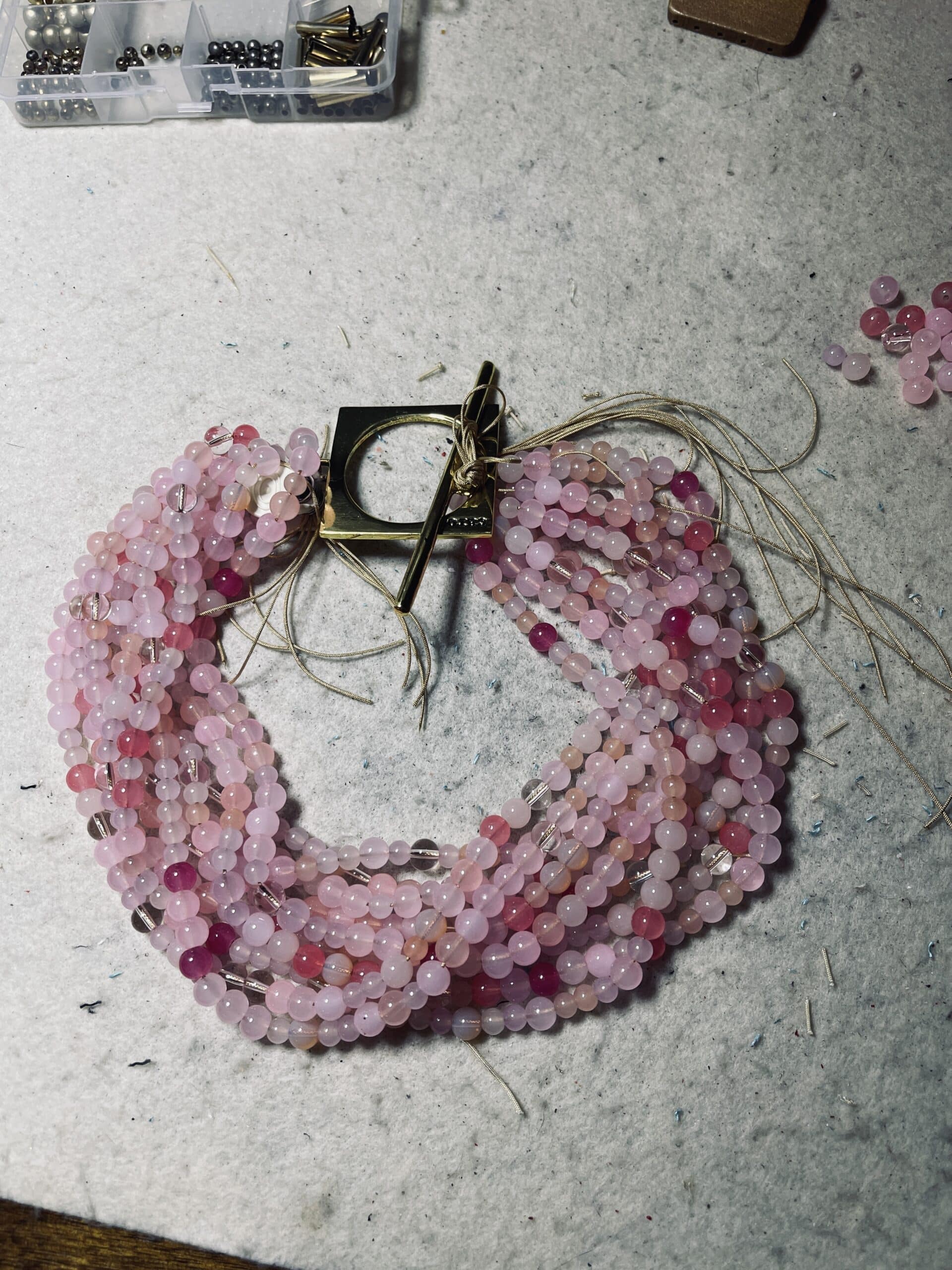 Make a bold statement with this Pink multi-strand glass bead necklace, designed to captivate with its rich texture and dynamic versatility. Measuring 22 inches in length and weighing 16 ounces, it offers a substantial yet graceful presence that complements both casual and formal attire. Crafted from small glass beads in varying shades of Pink, the strands create a layered effect that shimmers with movement and depth. Whether worn loose for a relaxed, bohemian vibe or twisted for a polished, evening-ready silhouette, this Pink necklace adapts effortlessly to your mood and style. A large gold toggle clasp anchors the design with a modern edge, positioned intentionally to rest on one side for an asymmetrical touch. The clasp’s geometric form adds contrast to the organic flow of the beads, elevating the piece with a sculptural accent. This necklace celebrates the beauty of color and craftsmanship, blending soft hues with bold structure. The Pink tones evoke warmth and femininity, while the gold clasp introduces a refined finish. Ideal for those who appreciate jewelry that transforms with intention, this piece invites you to express your individuality—one twist, one strand, one radiant moment at a time.