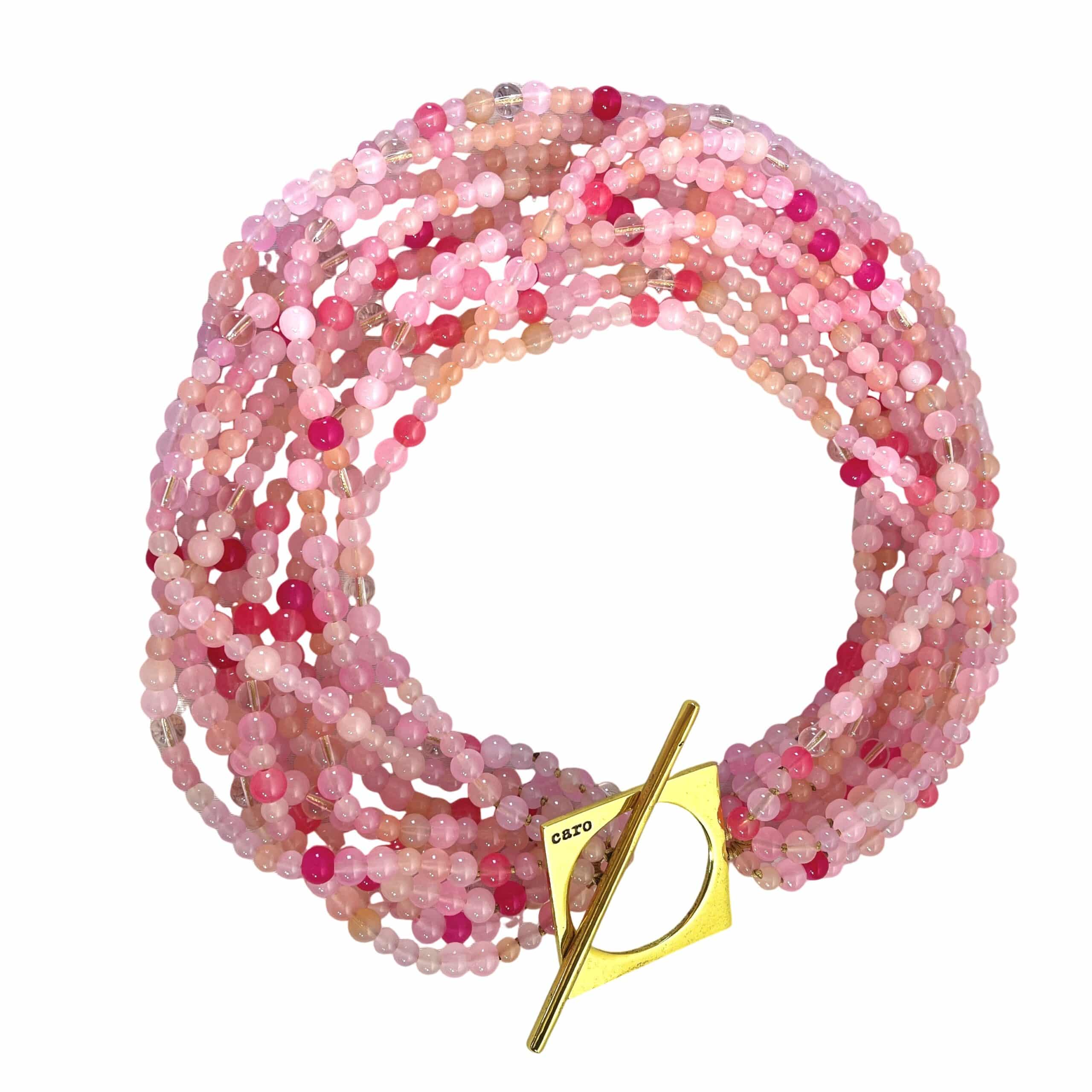 Make a bold statement with this Pink multi-strand glass bead necklace, designed to captivate with its rich texture and dynamic versatility. Measuring 22 inches in length and weighing 16 ounces, it offers a substantial yet graceful presence that complements both casual and formal attire. Crafted from small glass beads in varying shades of Pink, the strands create a layered effect that shimmers with movement and depth. Whether worn loose for a relaxed, bohemian vibe or twisted for a polished, evening-ready silhouette, this Pink necklace adapts effortlessly to your mood and style. A large gold toggle clasp anchors the design with a modern edge, positioned intentionally to rest on one side for an asymmetrical touch. The clasp’s geometric form adds contrast to the organic flow of the beads, elevating the piece with a sculptural accent. This necklace celebrates the beauty of color and craftsmanship, blending soft hues with bold structure. The Pink tones evoke warmth and femininity, while the gold clasp introduces a refined finish. Ideal for those who appreciate jewelry that transforms with intention, this piece invites you to express your individuality—one twist, one strand, one radiant moment at a time.