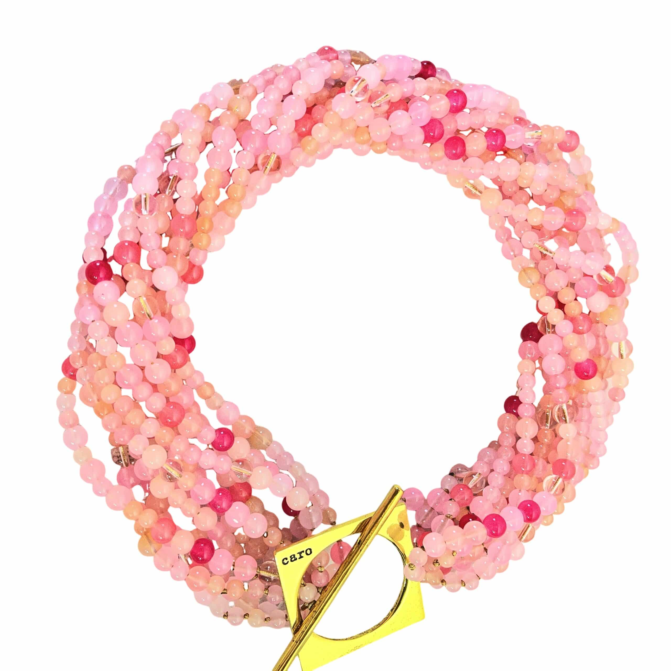 Make a bold statement with this Pink multi-strand glass bead necklace, designed to captivate with its rich texture and dynamic versatility. Measuring 22 inches in length and weighing 16 ounces, it offers a substantial yet graceful presence that complements both casual and formal attire. Crafted from small glass beads in varying shades of Pink, the strands create a layered effect that shimmers with movement and depth. Whether worn loose for a relaxed, bohemian vibe or twisted for a polished, evening-ready silhouette, this Pink necklace adapts effortlessly to your mood and style. A large gold toggle clasp anchors the design with a modern edge, positioned intentionally to rest on one side for an asymmetrical touch. The clasp’s geometric form adds contrast to the organic flow of the beads, elevating the piece with a sculptural accent. This necklace celebrates the beauty of color and craftsmanship, blending soft hues with bold structure. The Pink tones evoke warmth and femininity, while the gold clasp introduces a refined finish. Ideal for those who appreciate jewelry that transforms with intention, this piece invites you to express your individuality—one twist, one strand, one radiant moment at a time.