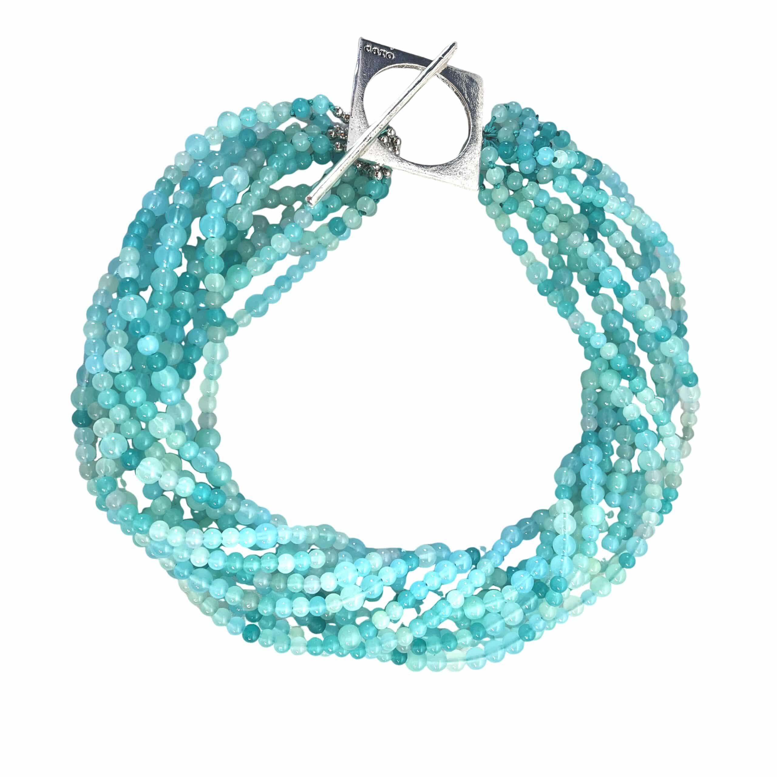 Elevate your ensemble with our Sky Cascade Necklace—a versatile statement piece inspired by the shifting hues of the open sky. This handcrafted design features multiple strands of petite glass beads in a harmonious gradient of blues, from deep ocean tones to the soft whisper of morning mist. Each bead catches the light like droplets suspended in air, creating a fluid, shimmering effect that evokes the serenity of a clear heaven at dawn. The necklace is anchored by a bold silver toggle clasp, intentionally placed to one side for a touch of asymmetrical elegance. This distinctive clasp not only secures the piece but adds a sculptural accent that complements both casual and formal looks. Wear it loose for a layered, bohemian vibe, or twist the strands for a more refined silhouette—perfect for evening wear or special occasions. Whether you're channeling the calm of a cloudless Sky or the depth of twilight blues, this necklace adapts to your mood and style. Designed for those who find beauty in nuance and movement, the necklace is more than an accessory—it’s a wearable reflection of nature’s palette and your personal expression. Let your style soar.