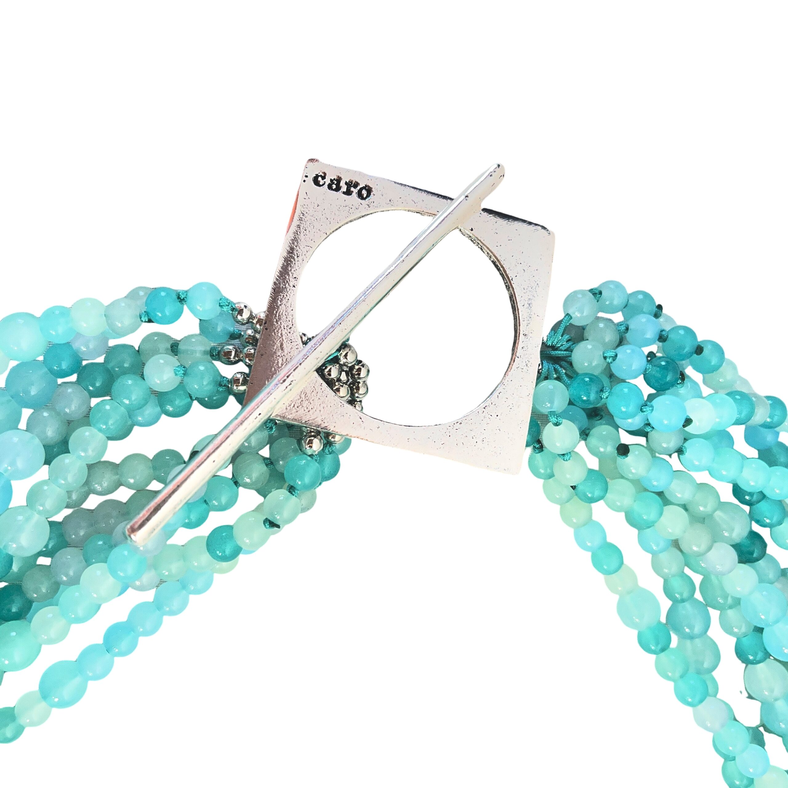 Elevate your ensemble with our Sky Cascade Necklace—a versatile statement piece inspired by the shifting hues of the open sky. This handcrafted design features multiple strands of petite glass beads in a harmonious gradient of blues, from deep ocean tones to the soft whisper of morning mist. Each bead catches the light like droplets suspended in air, creating a fluid, shimmering effect that evokes the serenity of a clear heaven at dawn. The necklace is anchored by a bold silver toggle clasp, intentionally placed to one side for a touch of asymmetrical elegance. This distinctive clasp not only secures the piece but adds a sculptural accent that complements both casual and formal looks. Wear it loose for a layered, bohemian vibe, or twist the strands for a more refined silhouette—perfect for evening wear or special occasions. Whether you're channeling the calm of a cloudless Sky or the depth of twilight blues, this necklace adapts to your mood and style. Designed for those who find beauty in nuance and movement, the necklace is more than an accessory—it’s a wearable reflection of nature’s palette and your personal expression. Let your style soar.