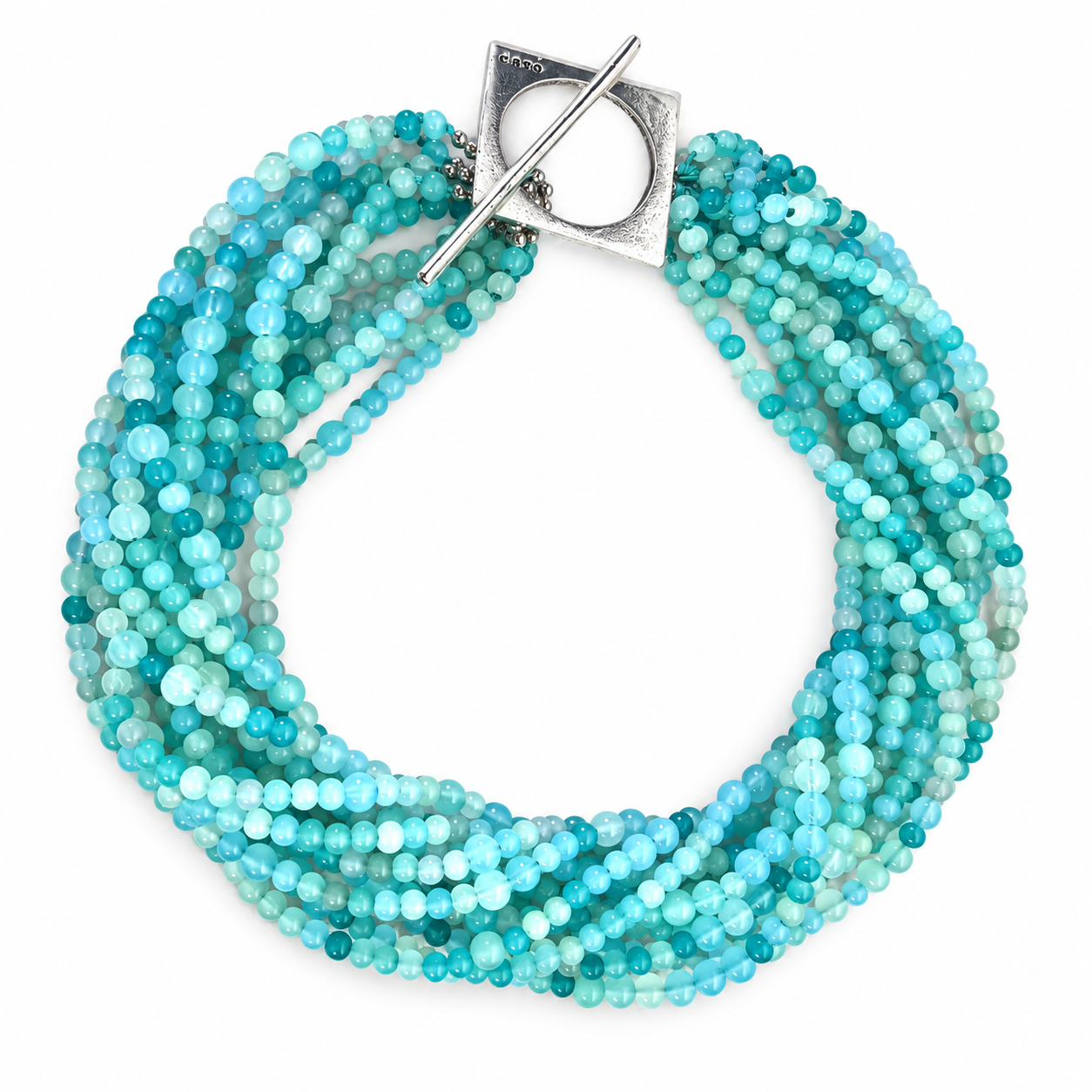 Multi-strand necklace made of small round glass beads in varying shades of turquoise, aqua, and sky blue. The strands are twisted together into a thick, rope-like form and secured with a large silver toggle clasp featuring a square plate and circular opening engraved with “caro.” The design evokes oceanic tones and fluid movement.