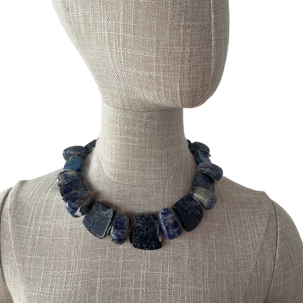 Zacatecas Necklace Where ancient stone meets modern elegance. This striking necklace blends flat Imperial Jasper with oval Sodalite stones, interspersed with gleaming silver spacer beads. The palette is a symphony of blues—deep navy, misty gray, and soft sky tones—each stone revealing its own marbled story. Measuring 18 inches with an extender reaching up to 22 inches, and weighing 8 ounces, it offers a substantial yet graceful presence around the neck. Imperial Jasper is revered for its grounding energy and intricate veining. The variety featured here hails from the rugged terrain of Zacatecas, Mexico, a region known for its rich deposits of semiprecious stones. Nestled in the Sierra Madre Occidental, Zacatecas has been a source of mineral beauty for centuries, with Imperial Jasper prized for its durability and spiritual symbolism. Sodalite, with its celestial blue hues, complements the Jasper’s earthy elegance, adding depth and contrast. Together, they create a piece that feels both ancient and contemporary—a wearable tribute to the artistry of nature and the legacy of Zacatecas. Whether paired with linen or leather, this necklace commands attention. It’s not just jewelry—it’s a journey through stone, history, and the soul of Zacatecas. Let its blues speak for you, three times over.