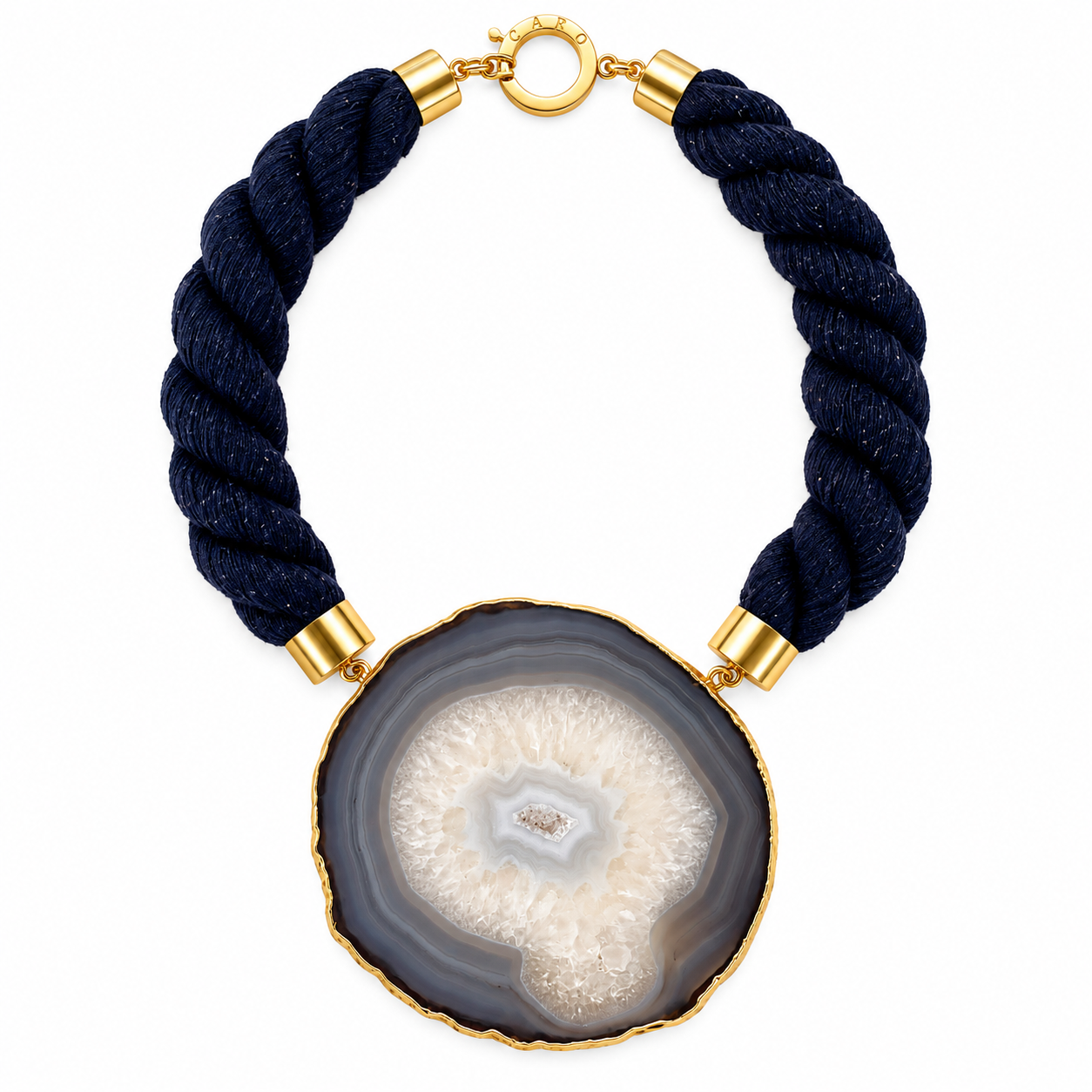 Statement necklace featuring a large circular sliced agate pendant with concentric layers of gray, white, and beige tones. The pendant is attached to a thick, twisted navy rope with gold metal caps and a round clasp, combining natural stone elegance with modern craftsmanship.
