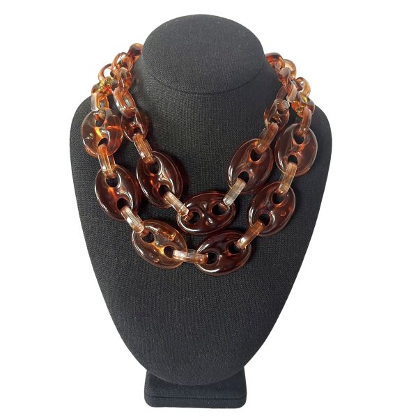 Revel Necklace Bold geometry. Glossy allure. Effortless drama. Crafted from oversized acrylic links, this double-strand necklace is a celebration of sculptural simplicity and modern edge. Each translucent loop catches the light with a tortoiseshell gleam, creating a rhythmic cascade of amber and espresso tones that feel both timeless and daring. At 18 inches, the necklace sits gracefully at the collarbone, with an extender allowing up to 20 inches for versatile styling. Despite its bold presence, it weighs a mere 4 ounces—light enough for all-day wear, yet substantial enough to make a statement. Revel in the interplay of texture and tone. Revel in the ease of pairing it with everything from crisp white shirts to plunging necklines. Revel in the confidence it inspires. Whether worn solo or layered with minimalist chains, this piece transforms any outfit into a curated look. It’s not just an accessory—it’s a mood, a moment, a magnet for compliments. Designed for those who embrace boldness with grace, this necklace invites you to step into your spotlight. Let the links speak for themselves, and let your style do the talking.