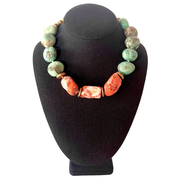 Truth Necklace Where color speaks and meaning resonates. This handcrafted necklace pairs the serene elegance of natural amazonite with the fiery vibrance of orange coral, creating a striking balance of calm and vitality. Measuring 18 inches with an extender reaching 23, it drapes gracefully across the collarbone, offering both comfort and presence at just 8 ounces. Amazonite, often called the “stone of truth,” is cherished for its soothing energy and its association with clarity, honesty, and heartfelt communication. Its greenish-blue hues evoke tranquil waters and open skies—an invitation to speak with authenticity and listen with compassion. At the center, bold coral beads add warmth and contrast, echoing the pulse of creativity and life force. Between each stone, natural coconut spacer beads lend an earthy texture and organic rhythm, grounding the piece in nature’s quiet wisdom. A decorative clasp with gold-toned accents completes the design with refined detail. Truth is not just a word—it’s a way of being. This necklace honors that principle, encouraging the wearer to embrace their voice, their story, their essence. Whether worn as a personal talisman or a statement accessory, it carries a quiet power that transcends trends. Truth in color. Truth in craftsmanship. Truth in you. Let this piece be your reminder to live and speak with intention.