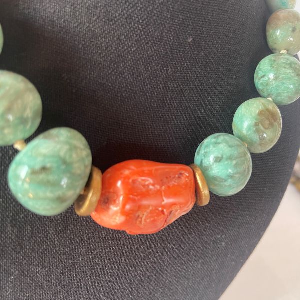 Amazon Necklace Rooted in nature. Radiant in spirit. This necklace is a tribute to the quiet power of simplicity. Crafted with natural amazonite beads in soft green-blue tones, it evokes the lush tranquility of riverbeds and forest canopies. At its heart lies a single coral stone—bold, warm, and unmistakably alive—anchoring the piece with a pulse of vibrant energy. Amazonite, known as the “stone of truth,” is celebrated for its calming influence and its ability to inspire honest expression. Its gentle hues mirror the serenity of the Amazon’s flowing waters, inviting clarity and emotional balance. The necklace’s 18-inch length, extendable to 23 inches, offers graceful drape and versatility, while its 8-ounce weight ensures a substantial yet comfortable presence. Natural coconut spacer beads add an earthy rhythm between the stones, enhancing the organic harmony of the design. A decorative clasp with gold-toned accents completes the look with artisanal finesse. Amazon is more than a name—it’s a feeling, a force, a connection to the wild and the wise. This necklace channels that essence, offering a wearable reminder of strength in softness and truth in simplicity. Let it be your companion in moments of reflection, expression, and quiet confidence.