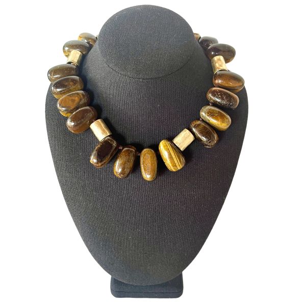 Taurus Necklace Earthy presence. Grounded elegance. Natural strength. This bold necklace is crafted from large, polished beads in warm, earthy tones that echo the steady, grounded nature of the Taurus spirit. Each bead carries its own organic striations and depth, creating a rich landscape of browns, ambers, and golden hues.  Cylindrical accent pieces add contrast and structure, giving the design a refined, architectural rhythm. Measuring 16 inches with an extender reaching 22, the necklace offers a versatile fit that sits beautifully along the neckline. Its 10‑ounce weight gives it a substantial, confident feel—perfect for those who appreciate jewelry with presence and intention. Taurus is known for its connection to the earth, its love of natural beauty, and its steady, loyal energy. This piece reflects those qualities through its grounded palette and its emphasis on natural materials. The warm tones evoke stability and comfort, while the polished finish adds a touch of sensuality that aligns with Taurus’s Venus‑ruled appreciation for tactile luxury. Whether worn as a statement of personal strength or simply as a striking accessory, this necklace brings warmth, balance, and a sense of rooted elegance to any look.