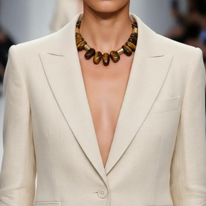 Taurus Necklace Earthy presence. Grounded elegance. Natural strength. This bold necklace is crafted from large, polished beads in warm, earthy tones that echo the steady, grounded nature of the Taurus spirit. Each bead carries its own organic striations and depth, creating a rich landscape of browns, ambers, and golden hues.  Cylindrical accent pieces add contrast and structure, giving the design a refined, architectural rhythm. Measuring 16 inches with an extender reaching 22, the necklace offers a versatile fit that sits beautifully along the neckline. Its 10‑ounce weight gives it a substantial, confident feel—perfect for those who appreciate jewelry with presence and intention. Taurus is known for its connection to the earth, its love of natural beauty, and its steady, loyal energy. This piece reflects those qualities through its grounded palette and its emphasis on natural materials. The warm tones evoke stability and comfort, while the polished finish adds a touch of sensuality that aligns with Taurus’s Venus‑ruled appreciation for tactile luxury. Whether worn as a statement of personal strength or simply as a striking accessory, this necklace brings warmth, balance, and a sense of rooted elegance to any look.