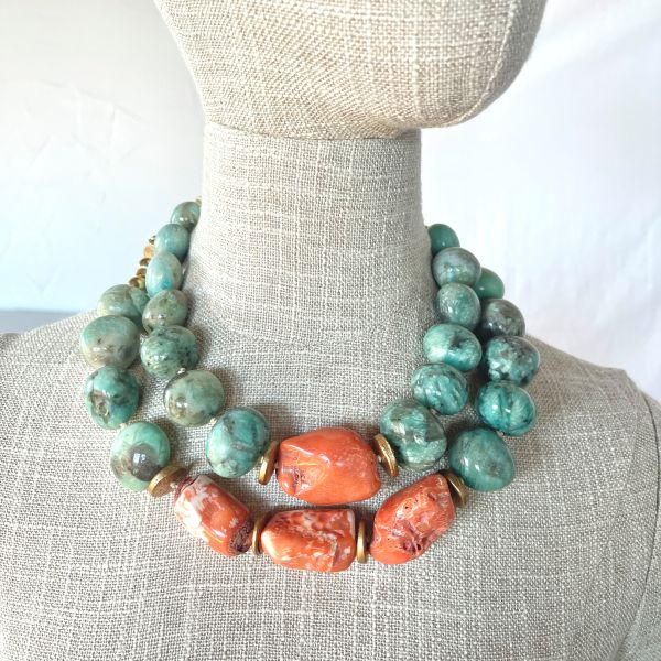 Amazonite Cluster Combo Layered color. Natural harmony. Effortless statement.   This Amazonite Cluster brings together two beautifully coordinated necklaces—products 0369242 and 0369243—designed to be worn as a striking layered duo or enjoyed individually. Each piece is crafted from natural amazonite, celebrated for its soothing blue‑green tones, and vibrant orange coral that adds a warm, energizing contrast. Gold‑accented coconut spacer beads introduce an earthy elegance, creating a balanced rhythm between color, texture, and shine. Both necklaces measure 18 inches in length and are fully adjustable, allowing you to achieve the perfect layered silhouette. When worn together, they create a bold, dimensional look that sits gracefully along the neckline. Combined, the two pieces weigh 14 ounces—substantial enough to feel luxurious, yet comfortable for all‑day wear. The Amazonite Cluster is ideal for those who love versatility. Wear the full combo for a dramatic, curated statement, or separate the pieces to suit your mood, outfit, or occasion. Each necklace stands beautifully on its own, yet together they form a cohesive, artful pairing that elevates any style. Whether you’re drawn to the calming presence of amazonite, the fiery charm of coral, or the richness of layered design, this combo offers endless ways to express your individuality.  You can purchase either piece separately by searching for the product number, or purchase this combo at a lower price.