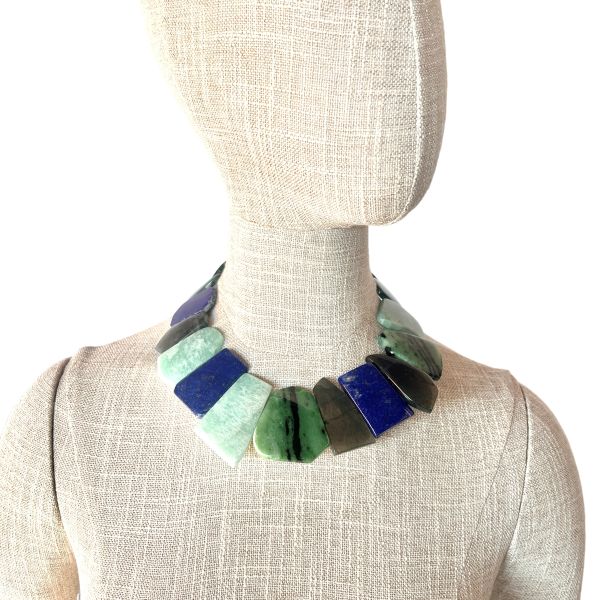 Multistone Harmony Necklace A celebration of Earth’s colors, textures, and ancient stories. This striking necklace brings together a curated ensemble of flat-cut Malachite, Lapis Lazuli, Labradorite, Nephrite, and Jadeite—each stone chosen for its natural beauty and its unique place in the world’s mineral heritage. The interplay of deep greens, oceanic blues, and iridescent grays creates a fluid, organic rhythm that feels both grounded and luminous. Measuring 15 to 20 inches with an adjustable extender and weighing 9 ounces, the piece drapes with a satisfying presence while remaining comfortable for all-day wear. Among these stones, Nephrite holds a special connection to Pounamu, the treasured greenstone of the Māori people of Aotearoa New Zealand. Historically, Pounamu was used not only for adornment but also for tools, weapons, and heirlooms passed down through generations. Its cultural significance is so profound that certain varieties of Pounamu were considered symbols of authority and guardianship. The combination of these storied stones transforms the necklace into more than an accessory—it becomes a wearable tapestry of geology, culture, and artistry. Each bead carries its own quiet power, and together they create a piece that feels timeless, expressive, and deeply connected to the natural world.