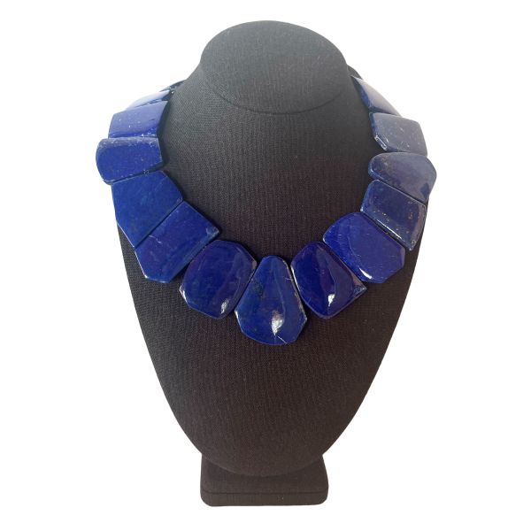 Asymmetric Lapis Elegance Necklace A deep‑blue statement shaped by history, artistry, and the Earth’s own palette. This captivating necklace is crafted from natural lapis stones, each one shaped into an asymmetric, flat form that highlights the mineral’s raw beauty. The deep celestial blues, touched with subtle golden specks, create a visual rhythm that feels both ancient and contemporary. Designed to rest gracefully along the neckline, the piece offers a bold yet refined presence—perfect for those who appreciate jewelry with character and story. Lapis has been treasured for over 6,000 years, admired by civilizations from Mesopotamia to Egypt. Cleopatra famously used powdered lapis as eyeshadow, and artisans of the Renaissance ground it into ultramarine pigment, once more valuable than gold. Its rich color and symbolic associations with wisdom, truth, and inner vision have made it one of the world’s most enduring gemstones. The natural variations in each stone ensure that no two necklaces are ever alike. With its striking silhouette and thoughtful composition, this necklace transforms the timeless beauty of Lazuli into a wearable work of art. Whether paired with everyday attire or reserved for special occasions, it brings forward a sense of depth, elegance, and ancient allure.