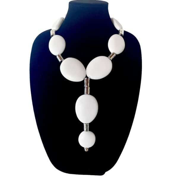 Evoking the serene beauty of Schoolhouse Beach, this necklace captures the essence of simplicity and strength. Crafted from large, matte white oval beads, each element recalls the smooth, time-worn stones that line the shore—organic, tactile, and quietly powerful. Interspersed with sleek silver cylindrical accents, the composition balances softness with structure, creating a harmonious rhythm that feels both modern and timeless. At its center, a pendant drop formed from matching beads adds a sculptural touch, drawing the eye downward in a graceful Y-shape. Measuring 21 inches in length and weighing 9 ounces, this piece offers a satisfying presence without overwhelming. The silver-toned carabiner clasp provides a secure closure while echoing the metallic accents throughout. This necklace is designed for those who appreciate the impact of a Single bold accessory. Whether worn with crisp linen, soft knits, or layered textures, it becomes a focal point—an expression of clarity and intention. The matte finish and gentle curves invite touch, while the clean lines speak to a minimalist aesthetic. Perfect for elevating everyday outfits or anchoring evening ensembles, this Single statement piece celebrates the beauty of restraint. Let it stand alone, or pair it with other favorites—either way, it remains unmistakably Single.