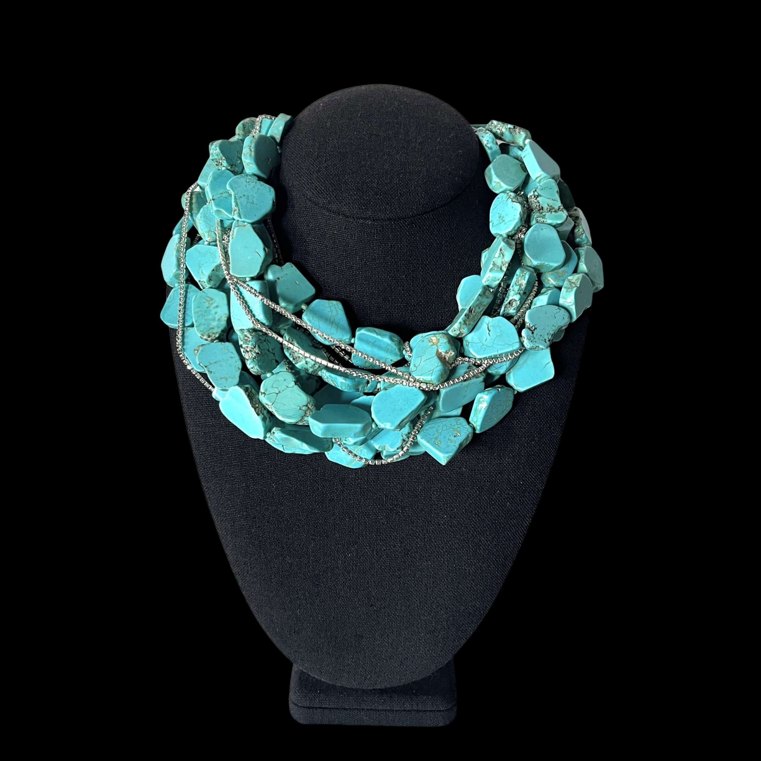 Make a bold statement with this multi-strand Tiel Chalcedony stone necklace, designed with rich texture, vibrant color, and elegant sparkle. The necklace features multiple strands of teal-colored chalcedony stones, each with a natural look that gives the piece depth and character. Strands of tiny Rhinestones are woven throughout, adding a delicate shimmer that beautifully complements the stones. Finished with a natural stone onyx toggle clasp, this necklace offers a refined contrast and a secure, stylish closure. Measuring 17 inches in length and weighing 18 ounces, it has a substantial feel while resting beautifully around the neckline. This Tiel Chalcedony necklace is perfect for dressing up a simple outfit or adding a unique finishing touch to evening wear. Its combination of natural stone, sparkle, and layered design makes it a standout piece for any jewelry collection. Chalcedony is a form of highly compacted quartz. 