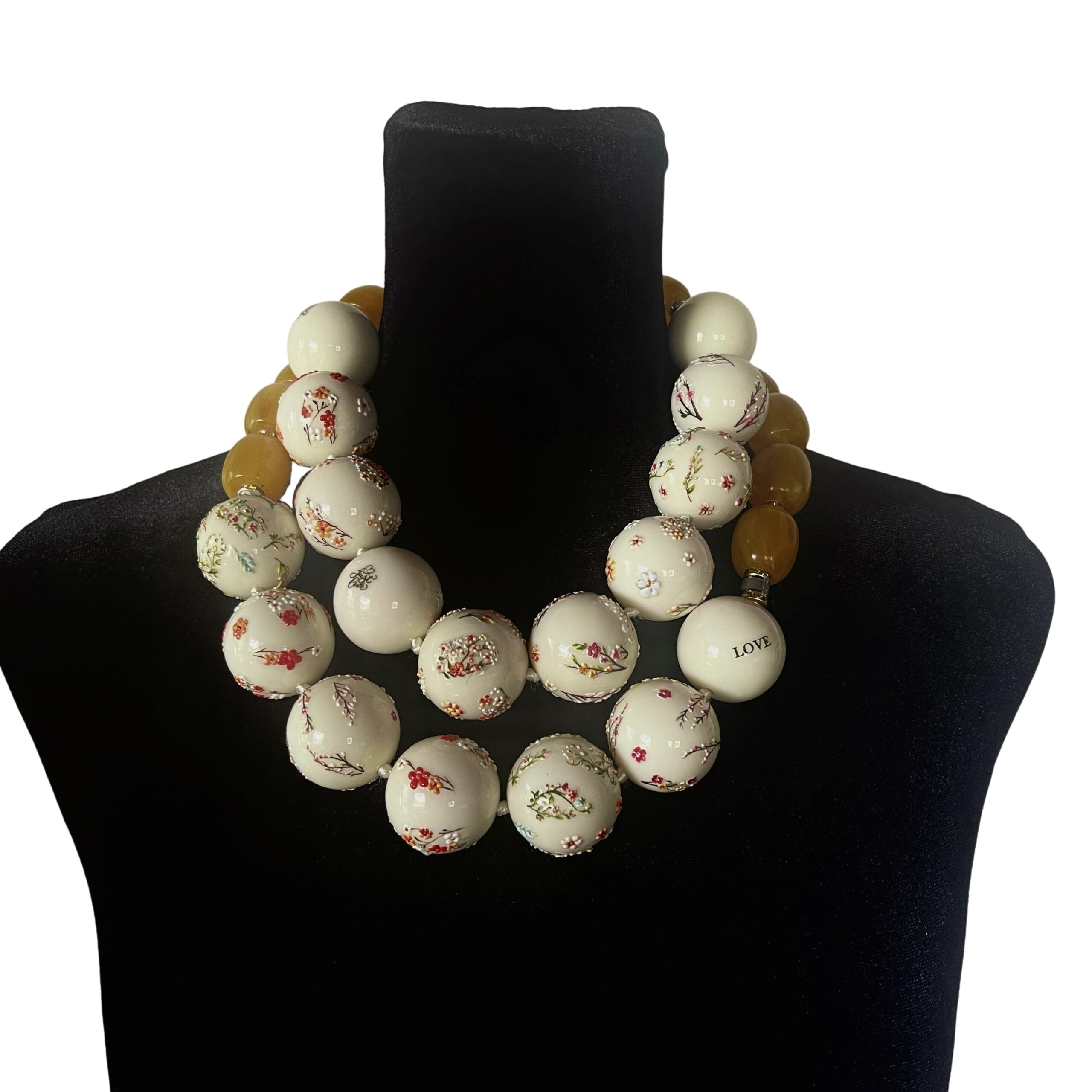 Two‑strand acrylic bead necklace set with floral designs and beeswax‑diluted yellow beads displayed on a black mannequin.