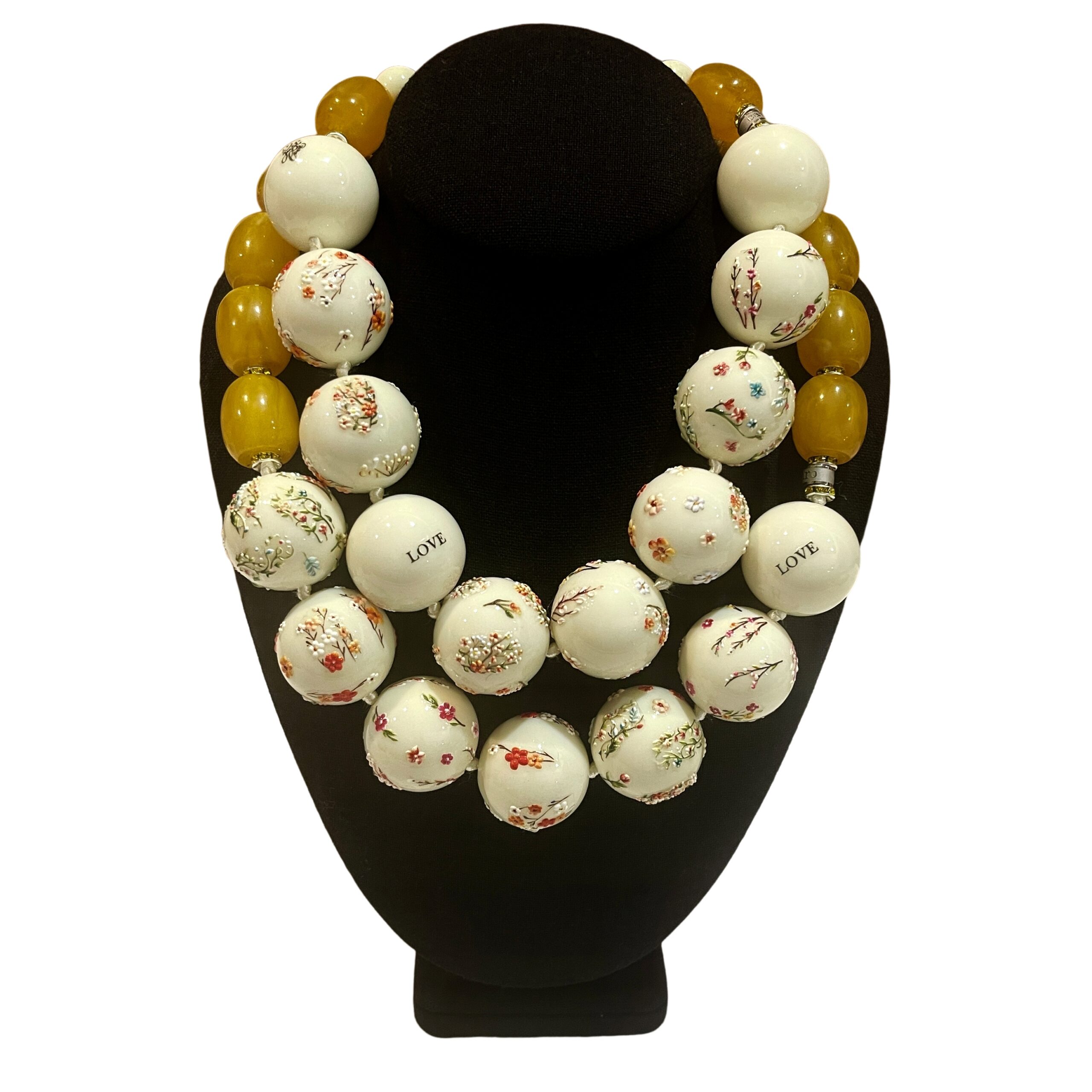 Two‑strand acrylic bead necklace set with floral designs and beeswax‑diluted yellow beads displayed on a black mannequin.