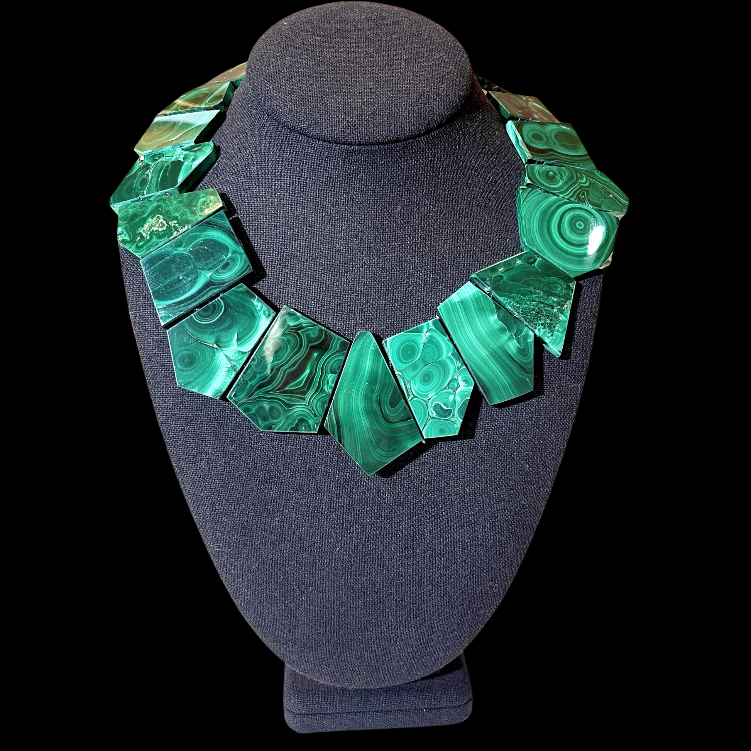 Natural malachite necklace with asymmetric green banded stones displayed on a linen mannequin