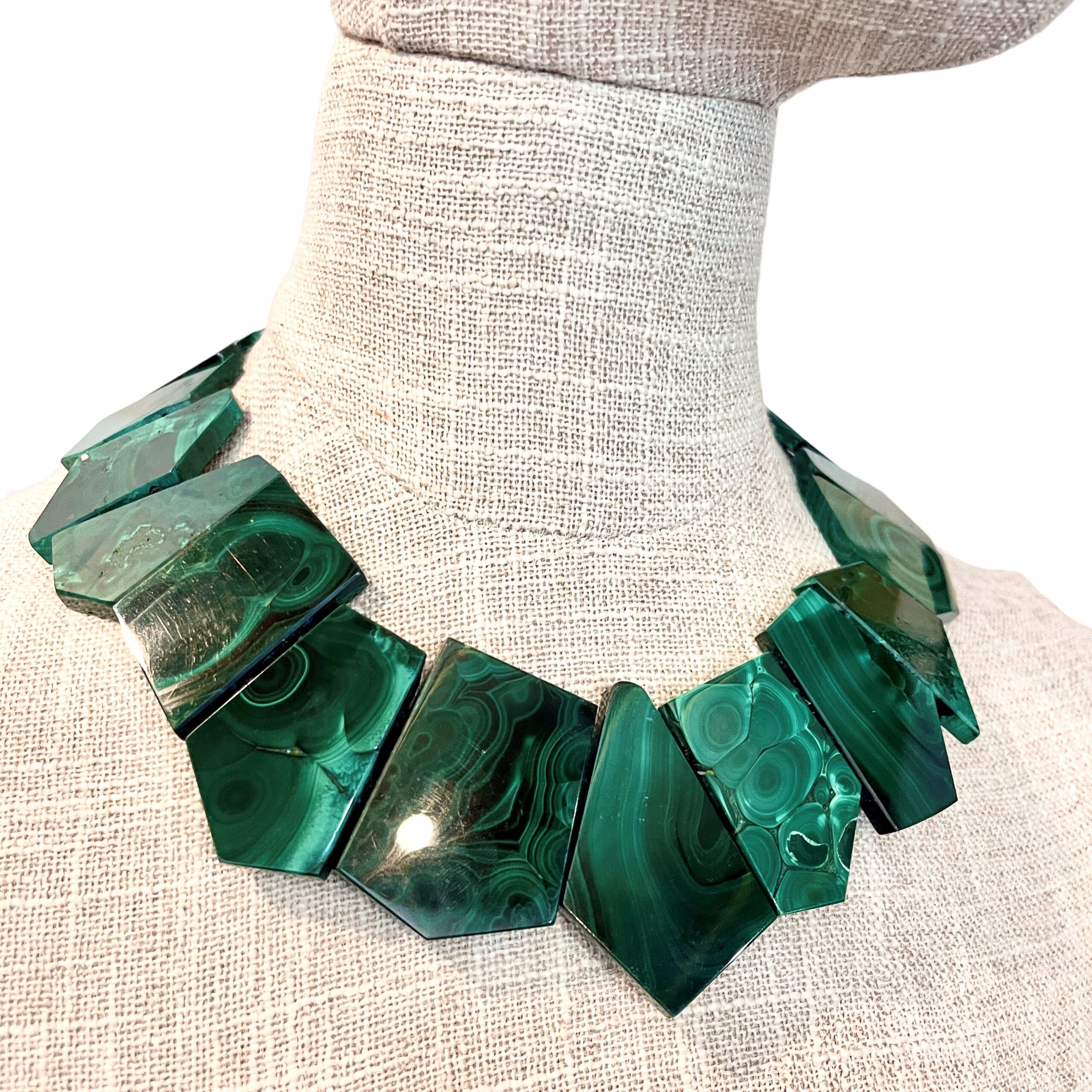 Natural malachite necklace with asymmetric green banded stones displayed on a linen mannequin